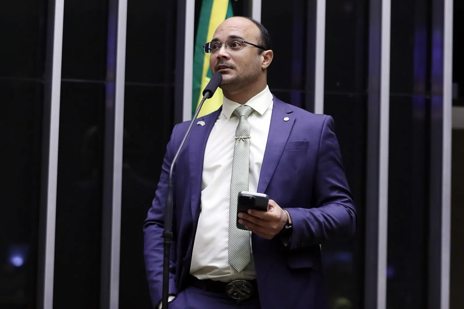 O deputado Capitão Alden fala à tribuna do plenário da Câmara com um celular na mão.