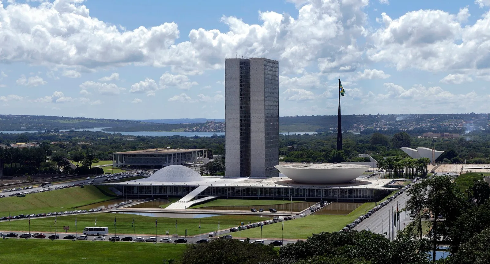 Fachada do Palácio do Congresso Nacional, em Brasília, com as duas torres de escritórios e as duas cúpulas dos plenários sob céu com nuvens.