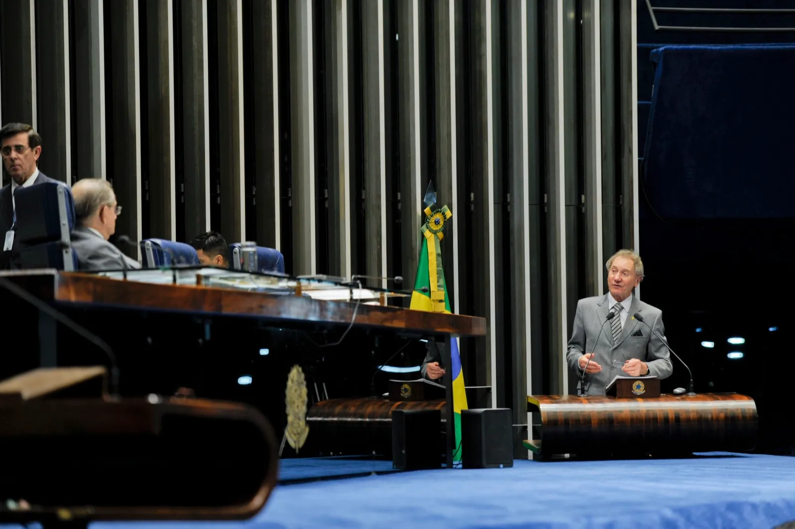 Plenário do Senado Federal, com um senador discursando na tribuna e a bandeira do Brasil ao fundo.