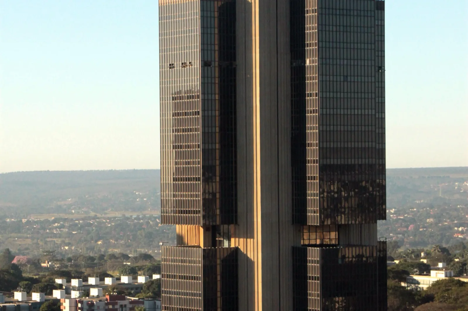 Torre de vidro escuro do edifício-sede do Banco Central do Brasil, em Brasília, com céu claro ao fundo.