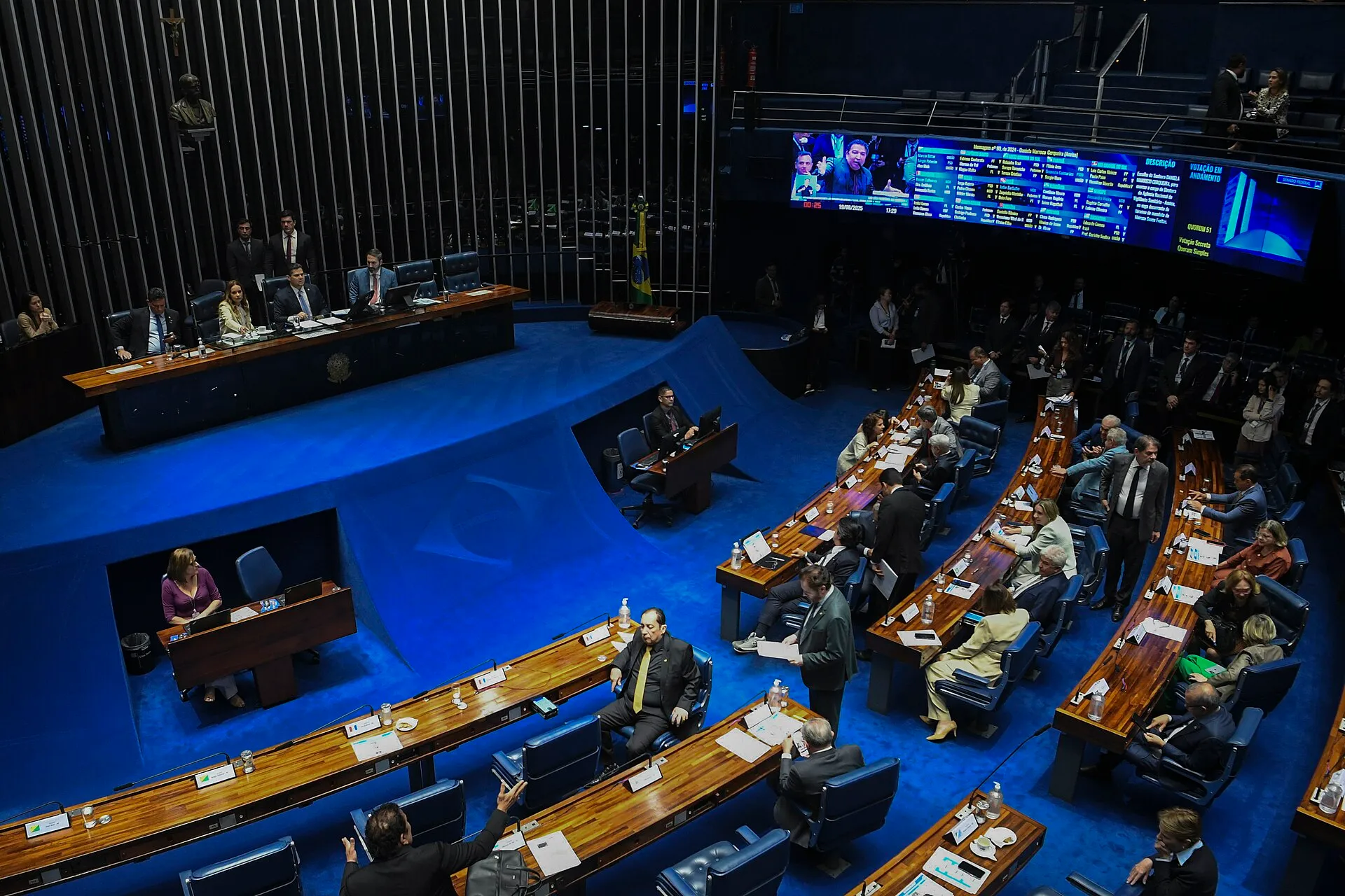 Plenário do Senado Federal durante uma sessão deliberativa, com os senadores em suas bancadas e o painel eletrônico exibindo uma votação em andamento.